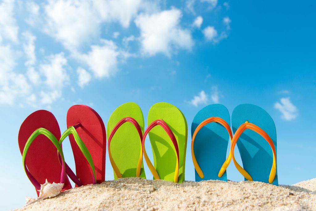 Row of colorful flip flops on beach against sunny sky Row of colorful flip flops on beach against sunny sky